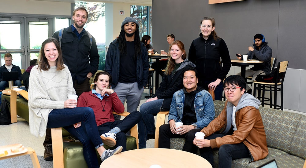 GT Students sitting in a lounge posing for a picture around a circular table.