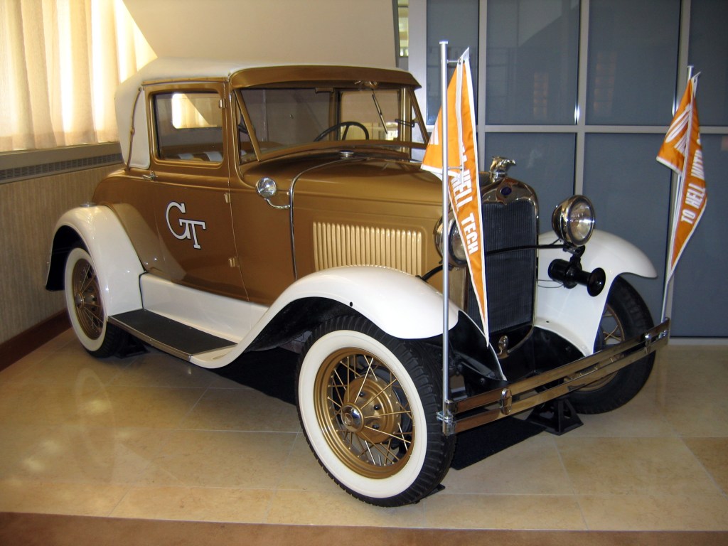 The Ramblin’ Reck, Georgia Tech’s iconic gold 1930 Ford Model A Sport coupe, parked with Georgia Tech flags mounted on the front.