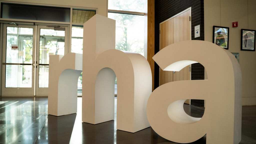 Large, freestanding white letters spelling "rha" inside a modern building.