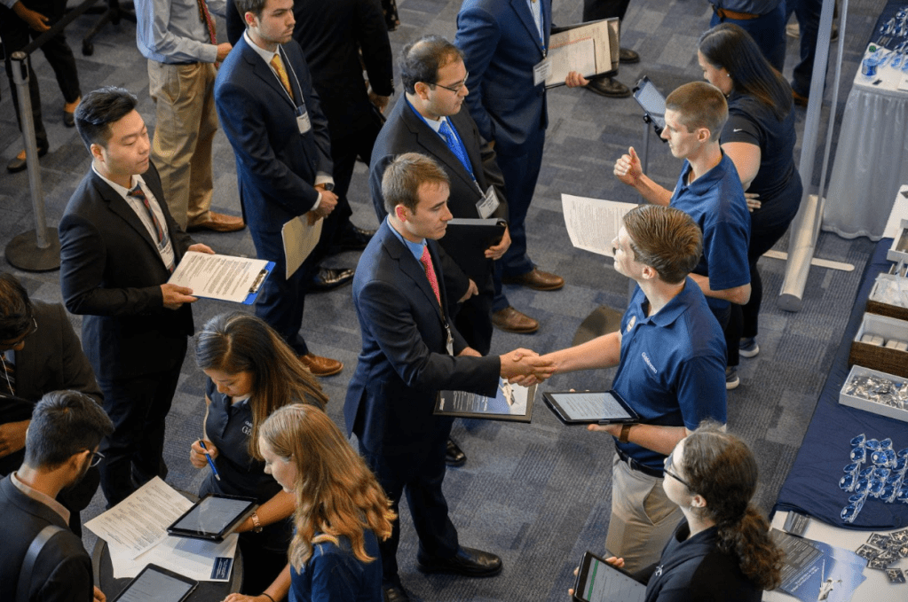 A top down view of formally-dressed students meeting employers at a career fair