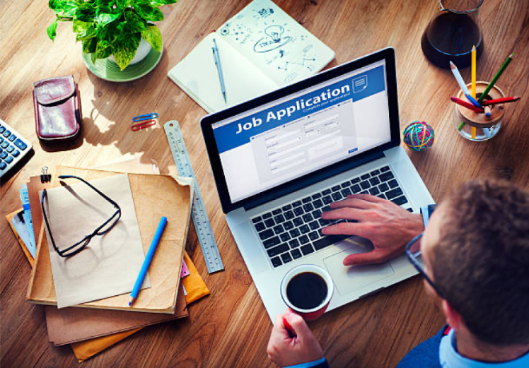 Semi-cluttered table with the focus on the computer displaying 'Job Application'