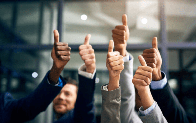 Several people group together holding up a thumbs up.