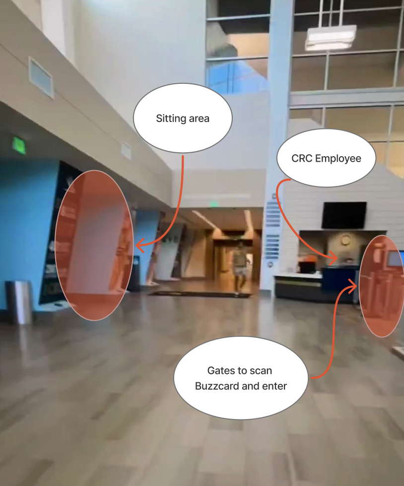 The image shows the interior of the Georgia Tech Campus Recreation Center (CRC) lobby immediately after entering through the main doors. The space has high ceilings, light-colored walls, and large windows allowing natural light to fill the area. To the left is a sitting area with chairs near a blue accent wall. To the right, a CRC employee stands behind the front desk, and just beyond the desk are gated turnstiles where students scan their BuzzCards to enter the facility. The floor is polished wood, and overhead lights add brightness to the open, modern lobby.