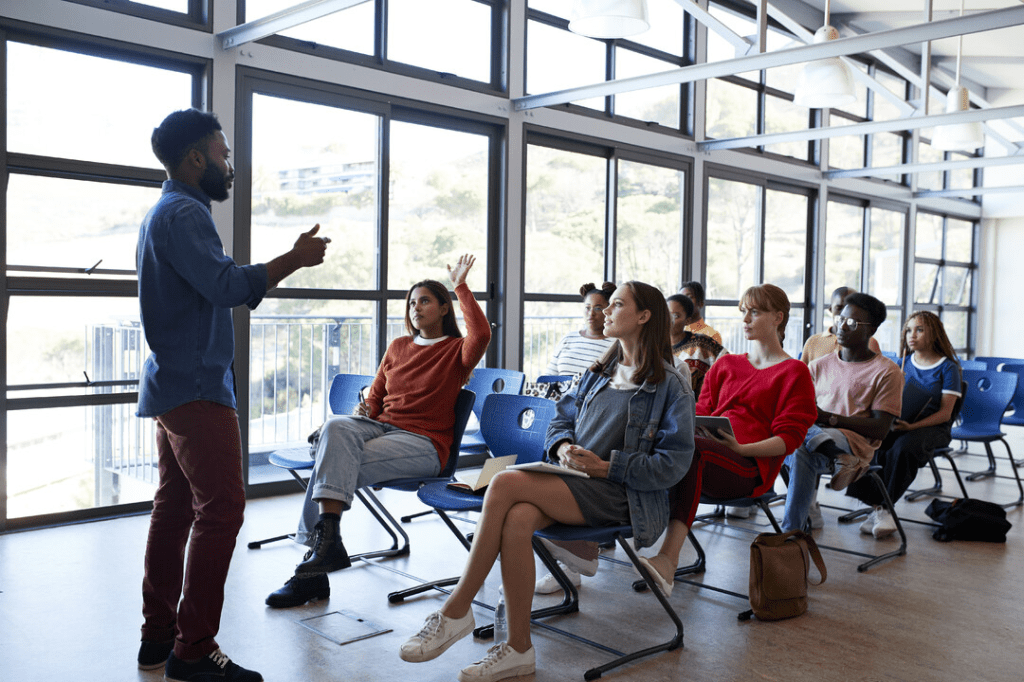 Teaching assistant leading a discussion with a small group of college students in a classroom.