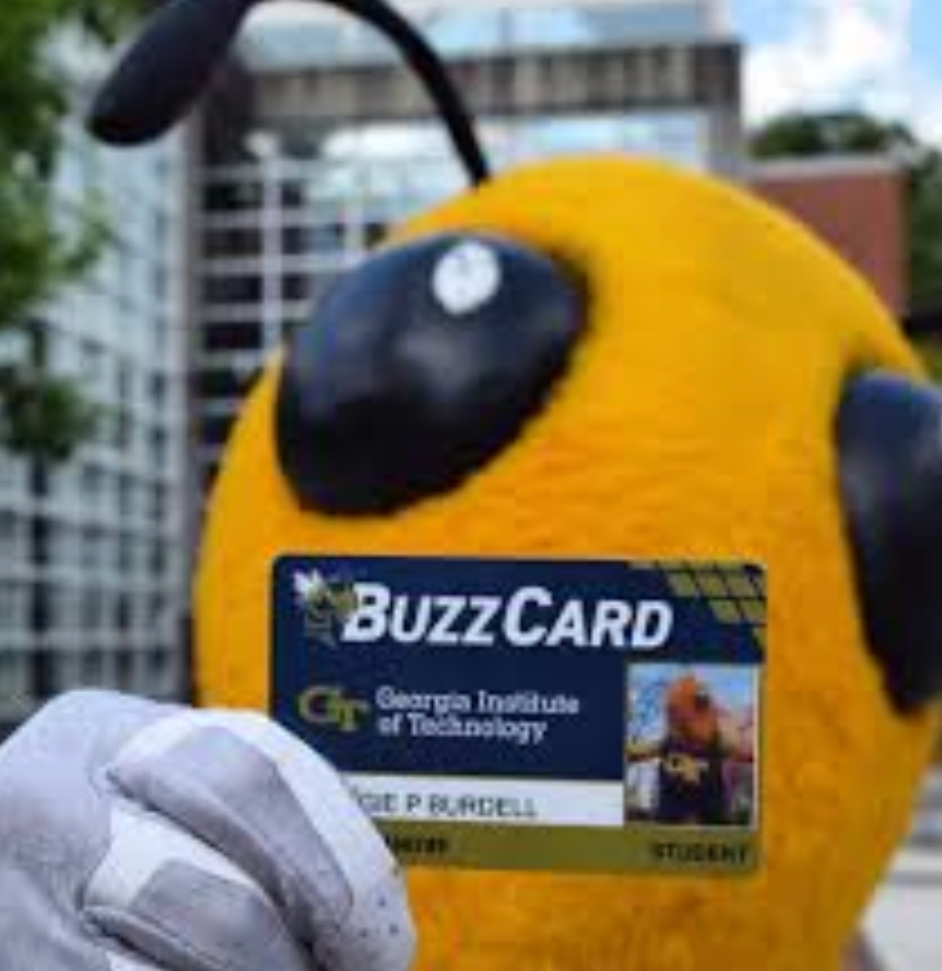Georgia Tech mascot holding a BuzzCard student ID card in front of campus buildings.
