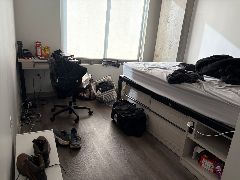 A messy bedroom with clothing on the floor.