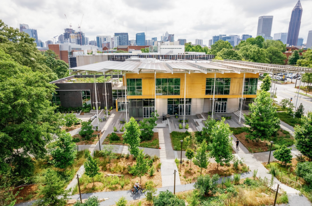 A photograph of the Kendeda Building’s landscaped outdoor area with trees, shaded seating, and natural design elements. All in the middle of the City of Atlanta