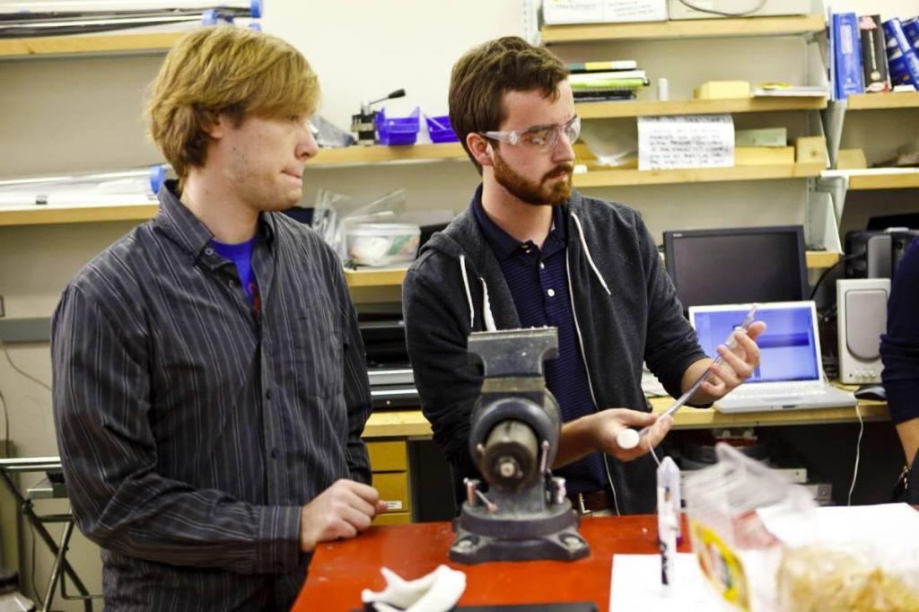Two students in the BME Design Shop demonstrating how to use a bench vise.