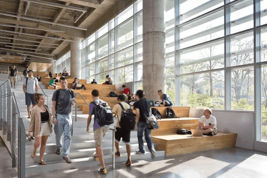 Students walk and sit in the bright, multi-level interior of Clough Commons.