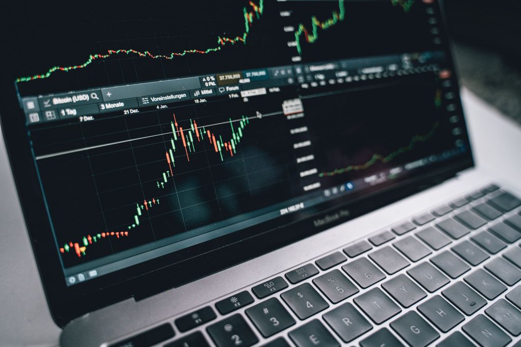 Laptop displaying a financial trading interface with stock price charts and market information.