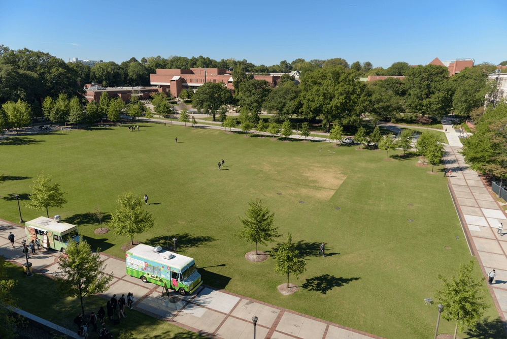 Aerial view of Tech Green with students walking near food trucks on a sunny day.